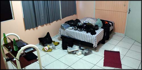 O quarto era arrumadinho e limpo. Era, até eu espalhar toda a bagagem...